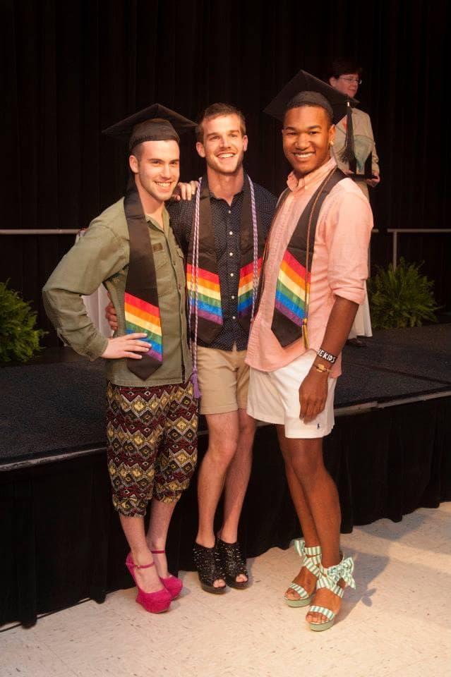 Three Lavendar Graduates wearing black stoles with rainbows.
