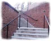 outdoor cement steps flanked by red brick walls leading upward to a landing.