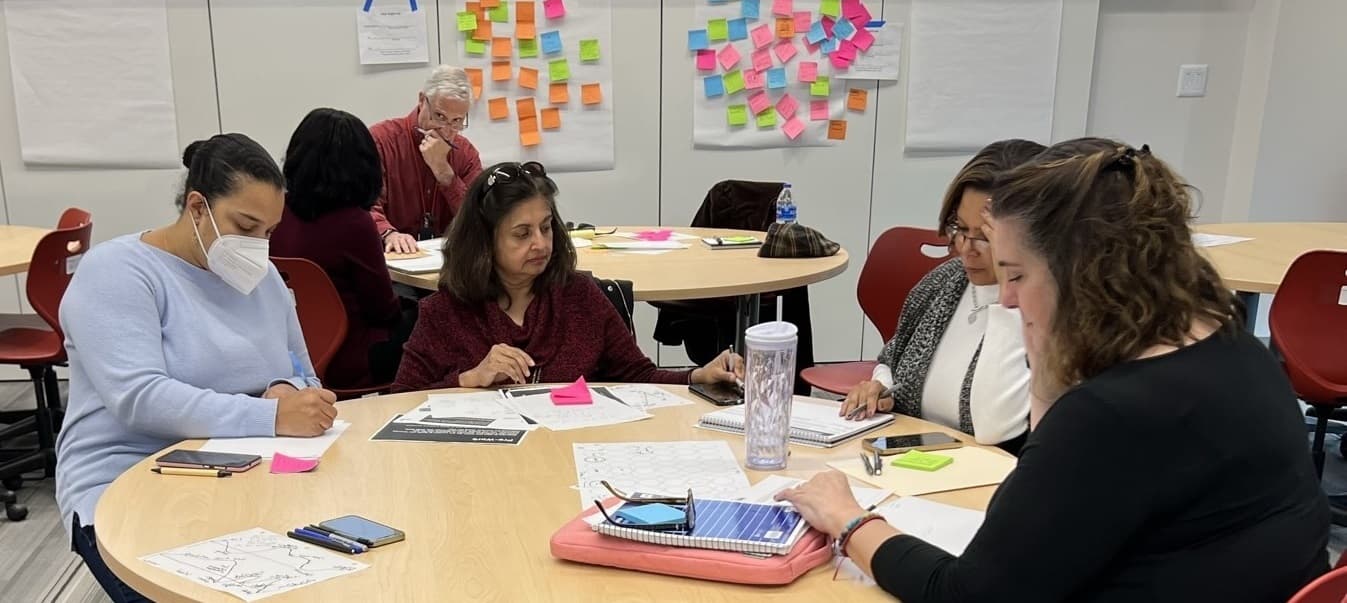 4 women sitting around a table working on an activity together.