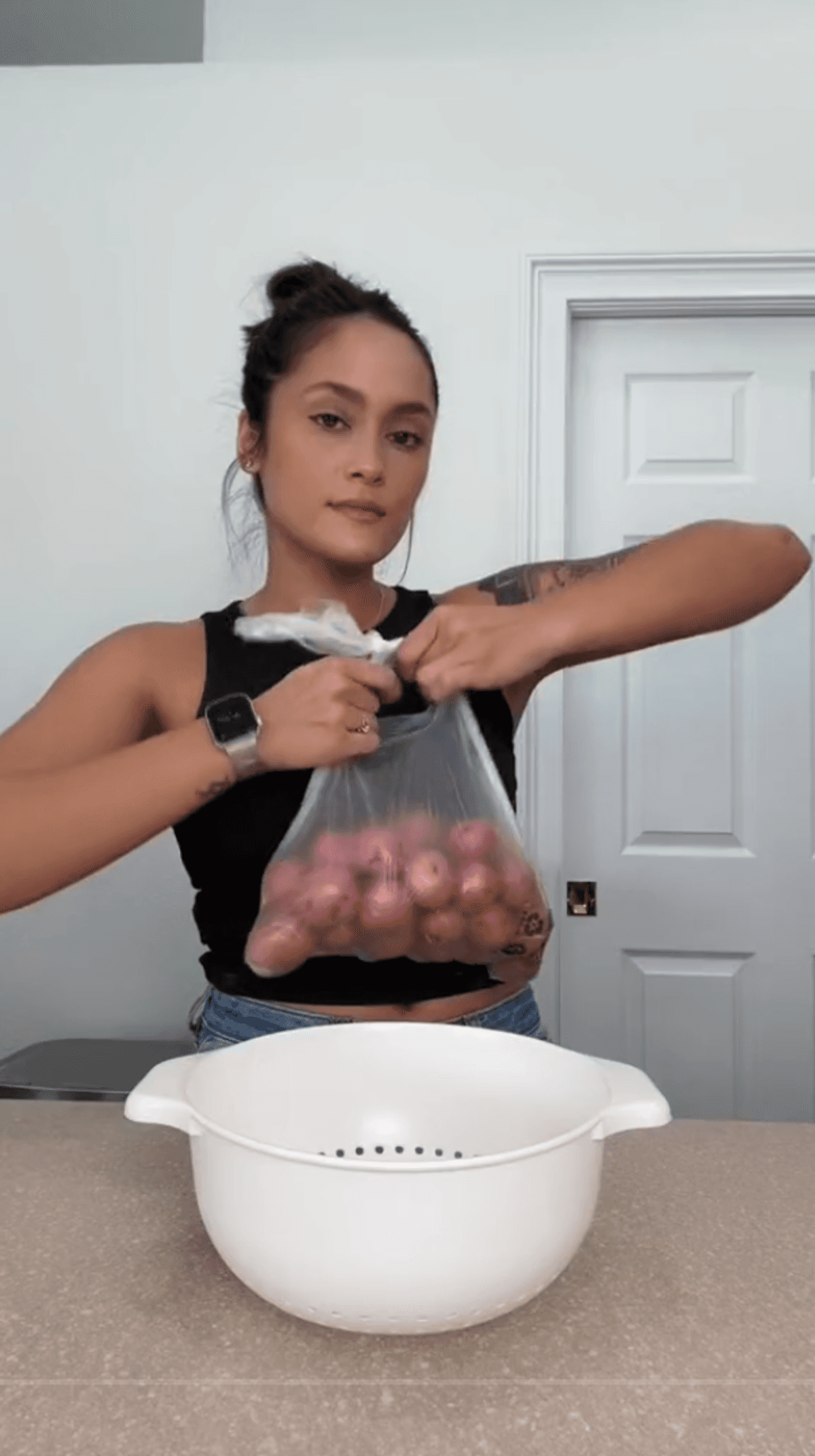 Person opening a bag of potatoes in front of counter.
