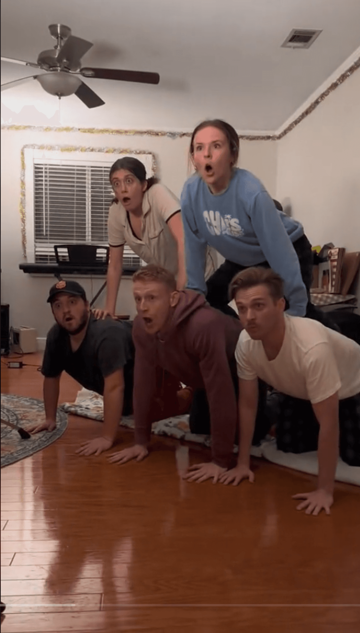 Five people in a living room forming a human pyramid.