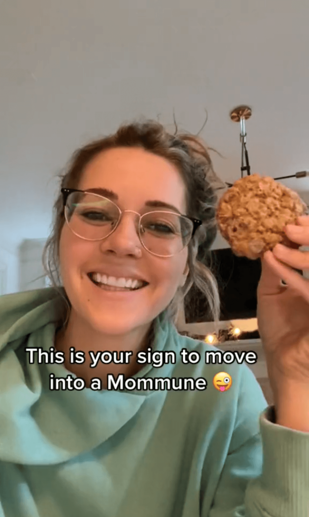 Person smiling holding a cookie and text that reads "This is your sign to move into a Mommune".