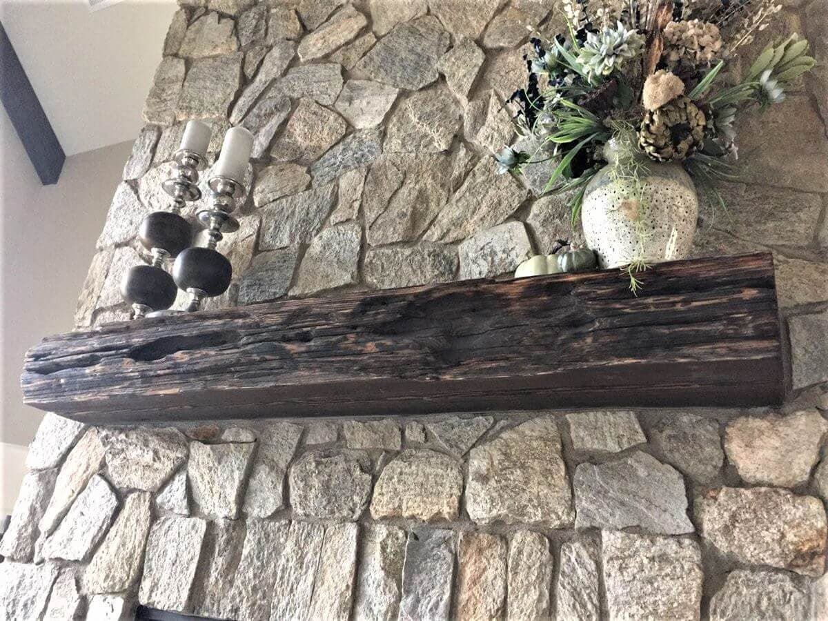 Shou sugi ban floating wood mantel on stone fireplace.