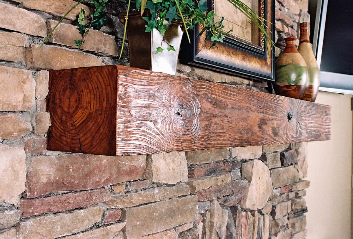 Wire Brushed Heart Pine fireplace Mantel Brown against a stone wall