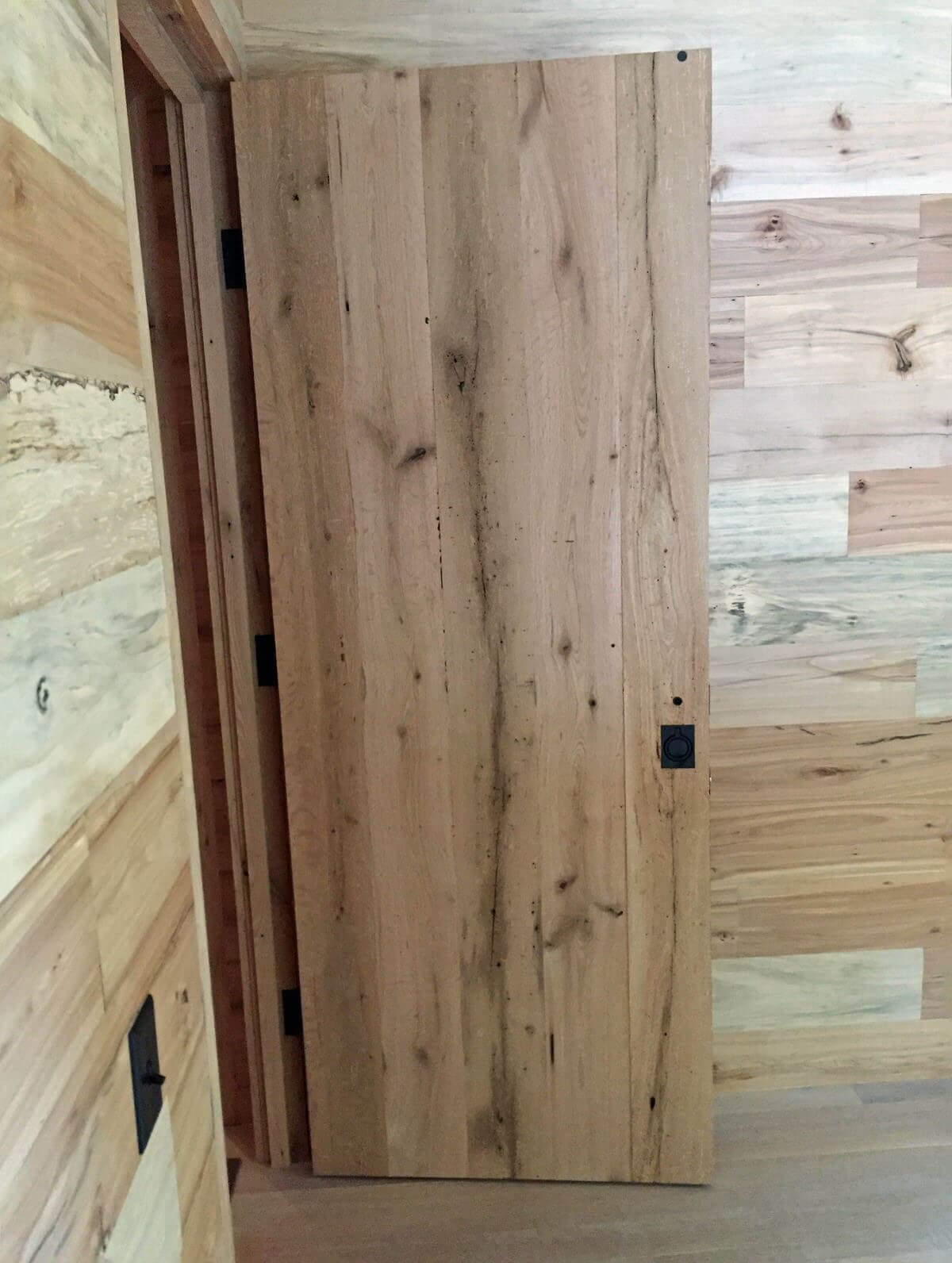 antique hardwood door in a room of mixed hardwoods wall cladding