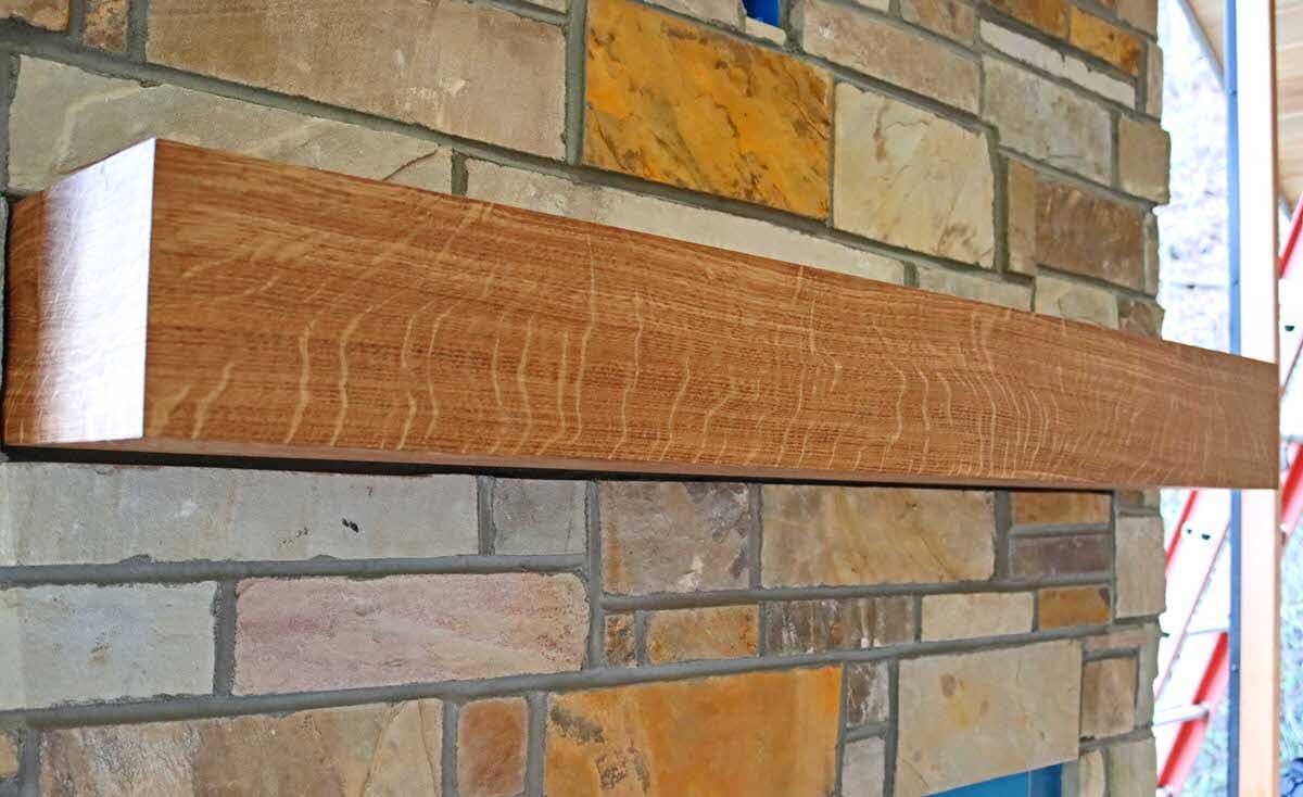 oak box mantel with wood rays against a brick Box fireplace