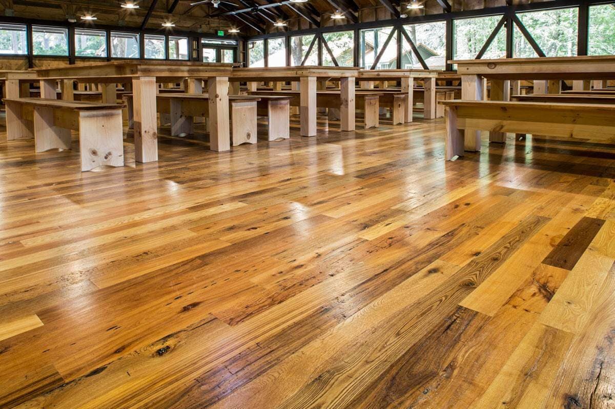 Classic smooth hardwood flooring in large rustic dining hall.