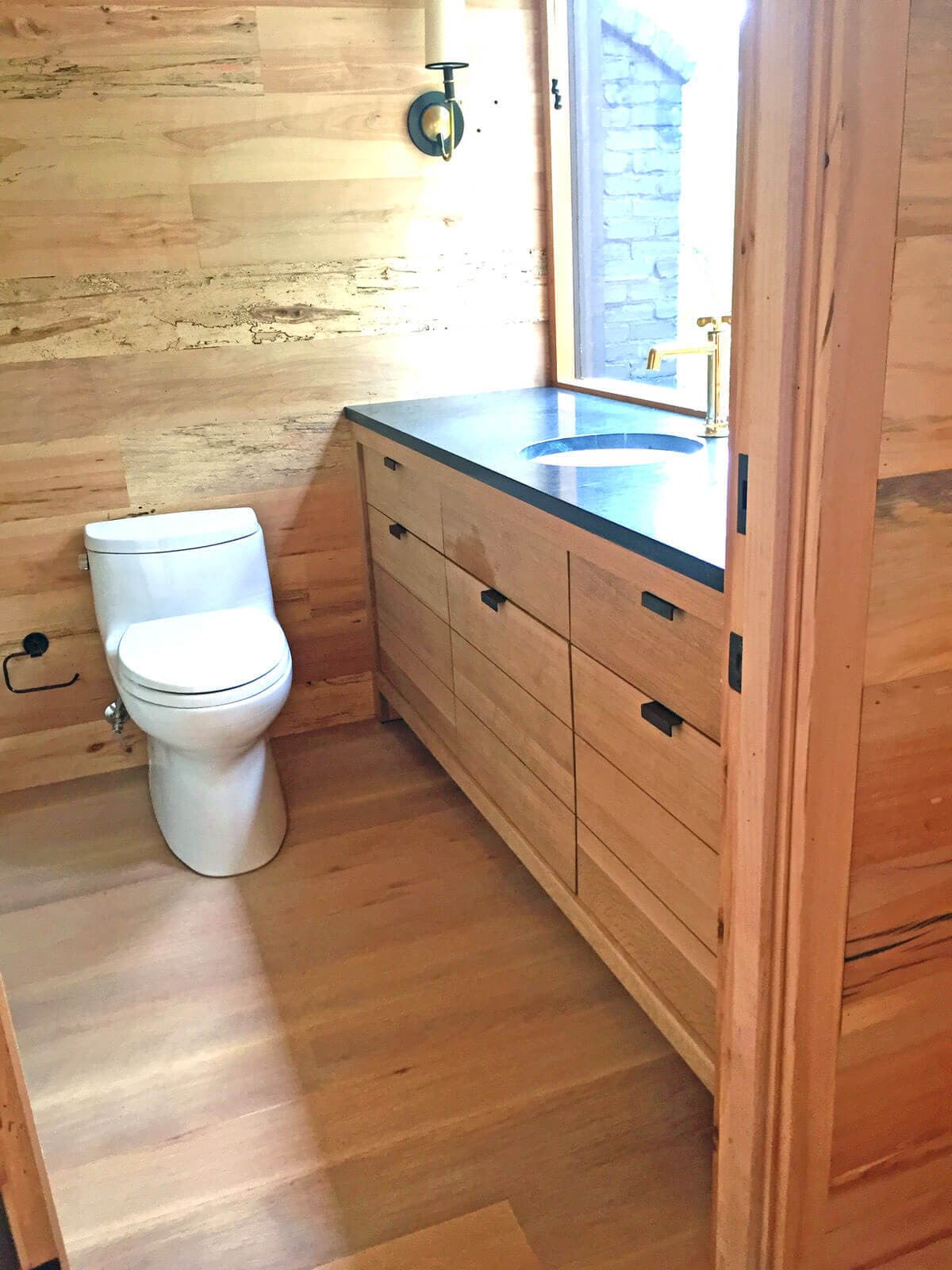 bathroom with toilet and smooth surface reclaimed hardwood paneling and cabinets
