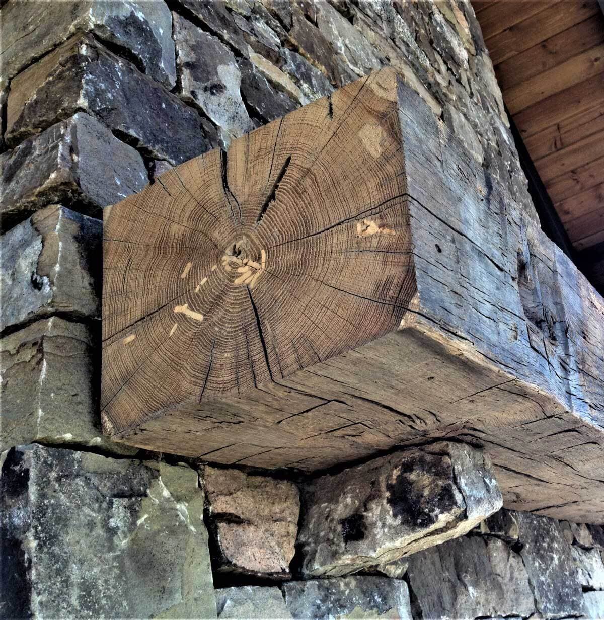 Hand hewn mantel mortise unfinished on stone fireplace.