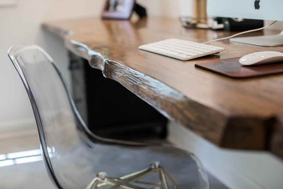 Live edge oak office table sideview closeup next to clear acrylic chair