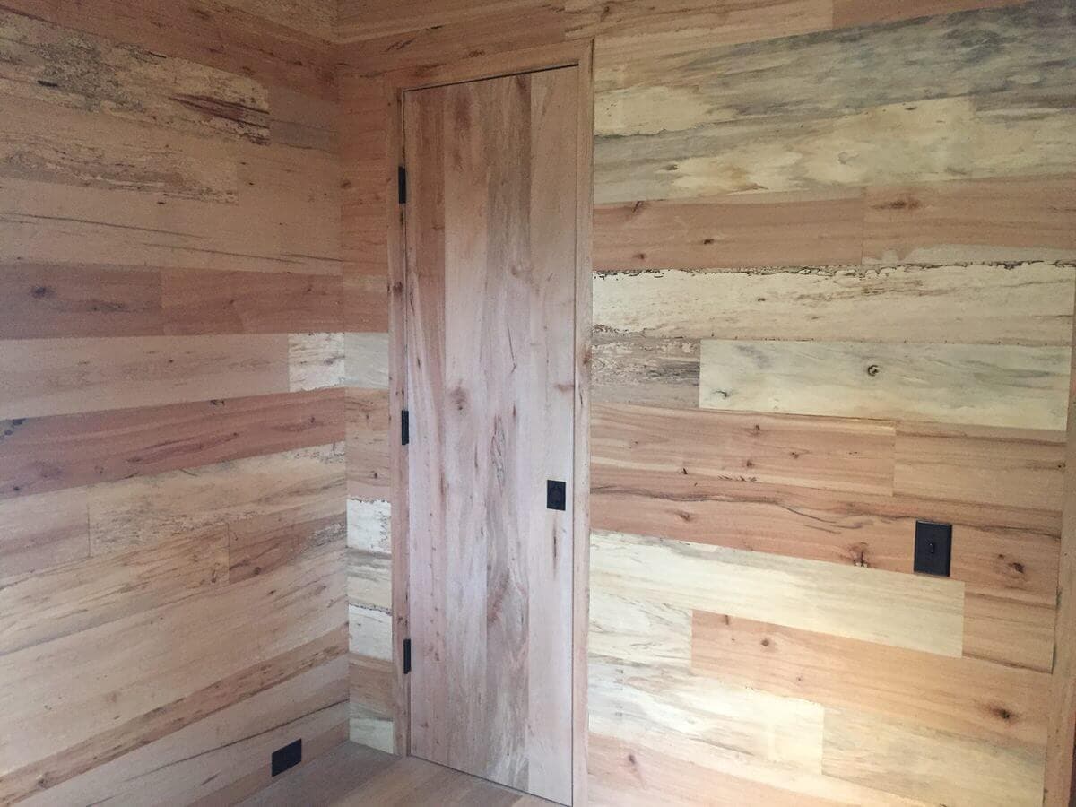 pale colored mixed hardwoods wall cladding with horizontal planks in a room with a door