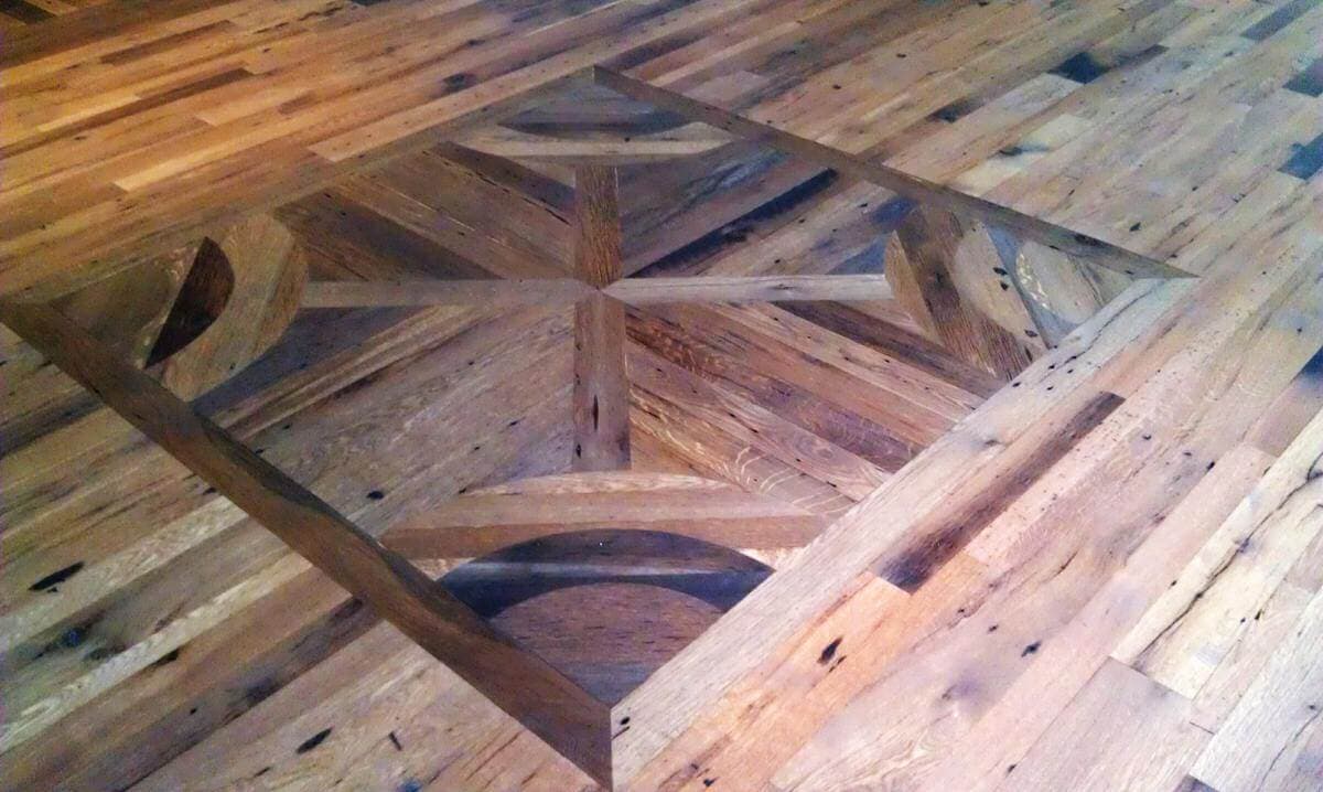 Reclaimed old wood boards become beautiful flooring with custom inlay.