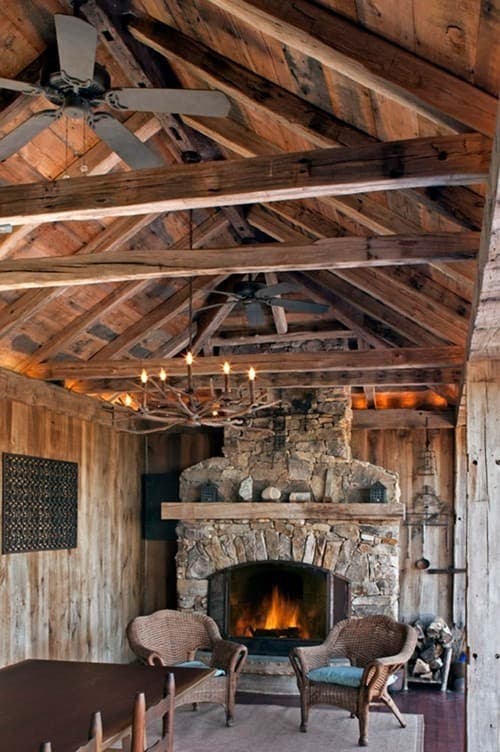 Solid reclaimed rustic wood beams define outdoor fireplace and dining area.