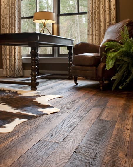 Reclaimed wood flooring with cowhide rug on top.