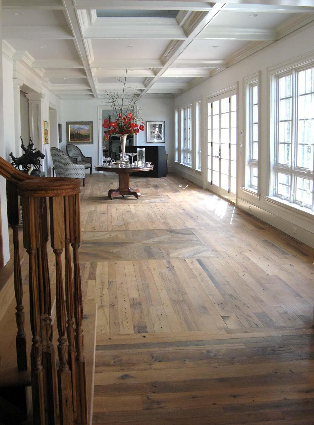 Reclaimed wood flooring in long living room with many windows.