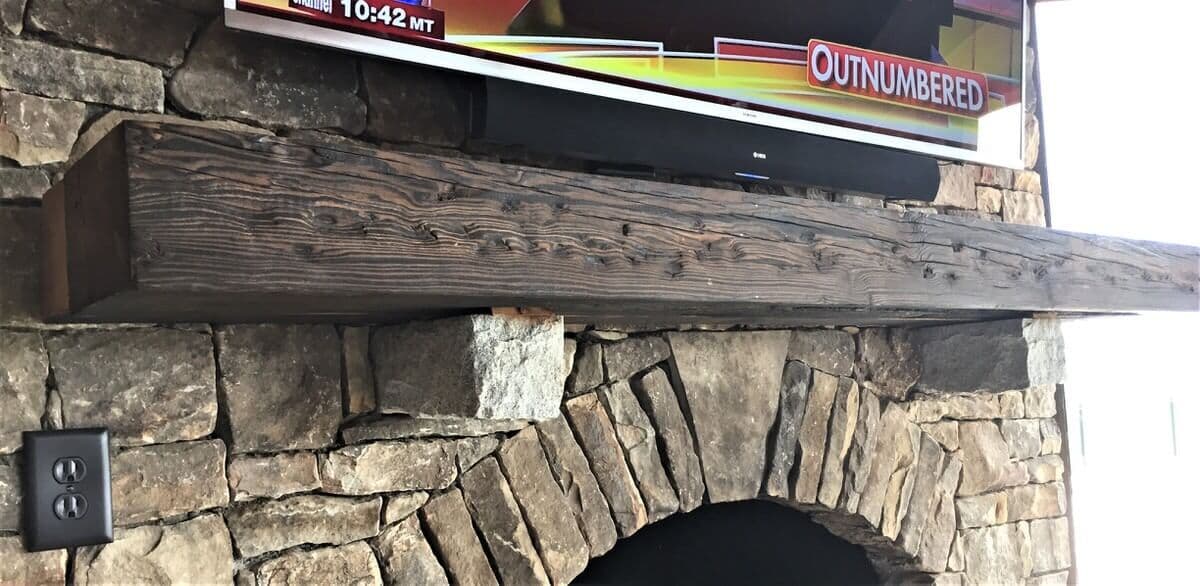 Shou sugi ban mantel on oval arched stone fireplace in lake toxaway nc