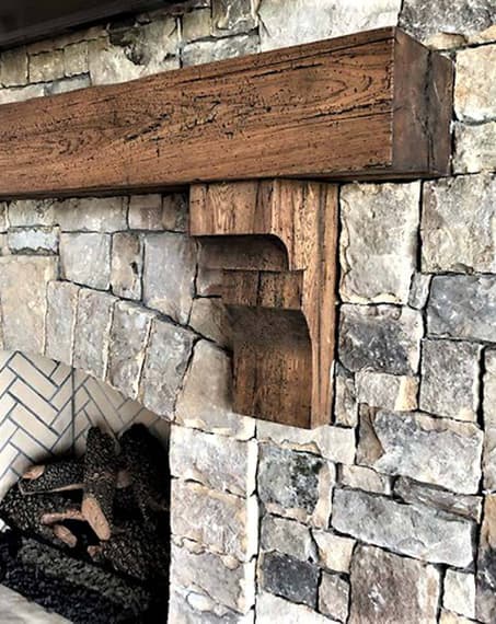 Reclaimed hickory mantel smooth planed and with corbels on stone fireplace.