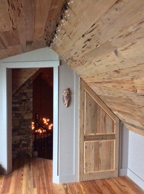 Reclaimed wood paneling for rustic wood panel ceiling accent in loft.