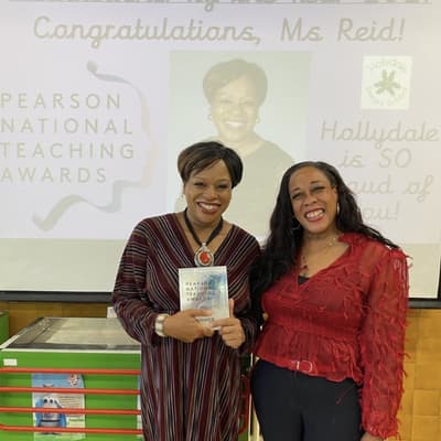 One person holding an award that reads “Pearson National Teaching Awards”, standing beside another person, both are smiling.