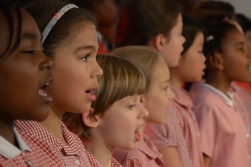 Children wearing red uniforms singing in a row.