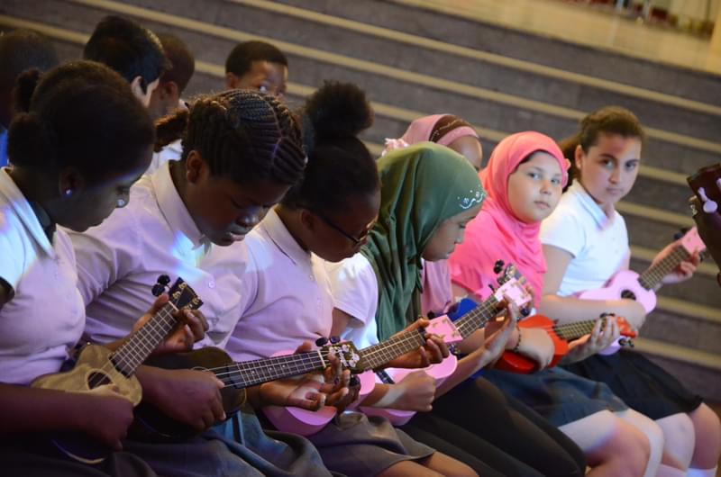 Children playing ukulele in a row.