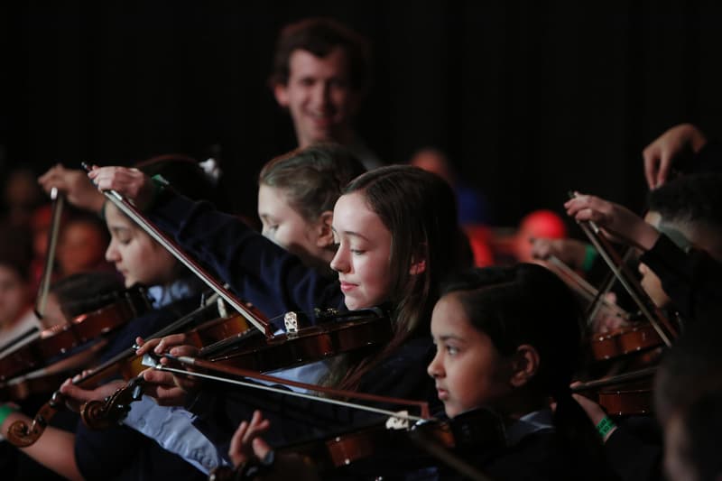 A group of young people playing violins.