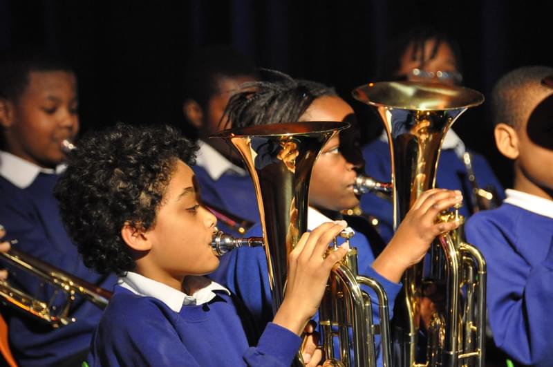 Children in blue uniforms playing the tuba