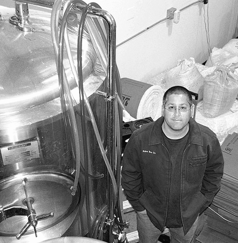 Co-founder David Kleban stands next to a large stainless steel brewing vessel in the company's original facility.