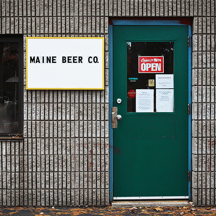 The entrance to Maine Beer Company's original facility in Portland with a simple white sign.