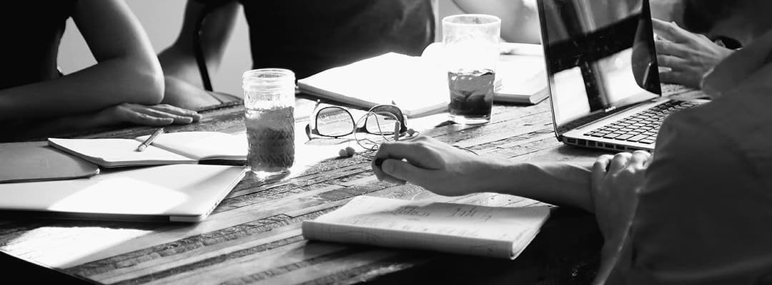 A black and white photo of people around a conference table