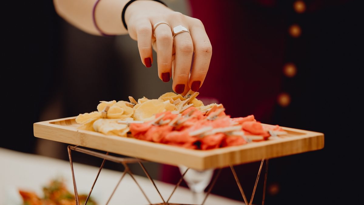 A woman's hand reaching towards a plate of fingerfood