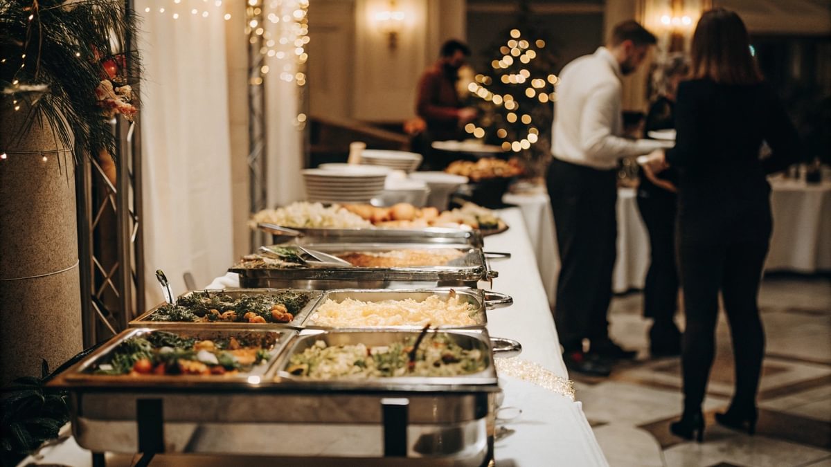 Buffet mit vielfältigen Speisen bei einer Veranstaltung in NRW, inklusive Salaten, warmen Gerichten und Desserts, Gäste bedienen sich in stilvoll dekorierter Location.
