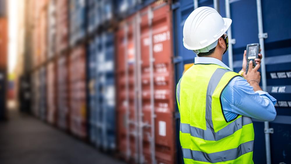 Worker scanning shipping containers with handheld device