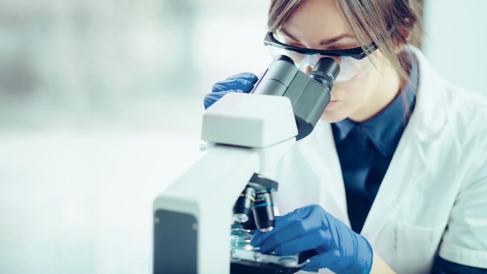Female scientist looking through a microscope in a laboratory