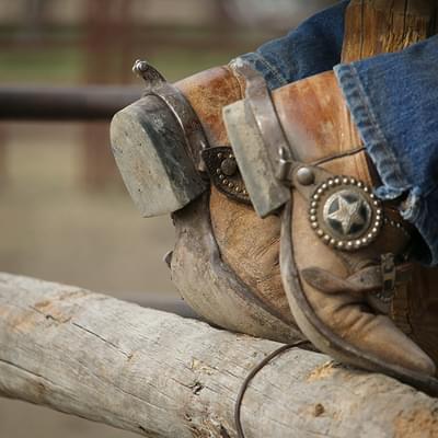 Cowboy boots on fencerail