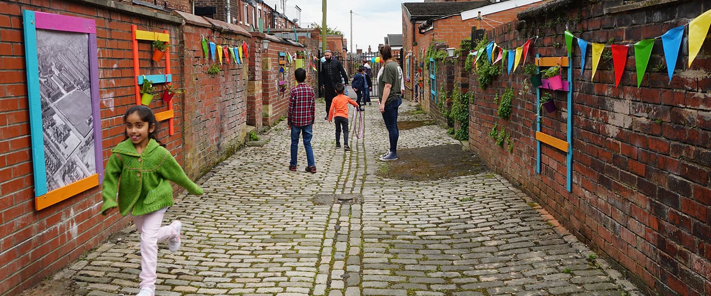A group of people walking down a colourfully decorated alleyway.