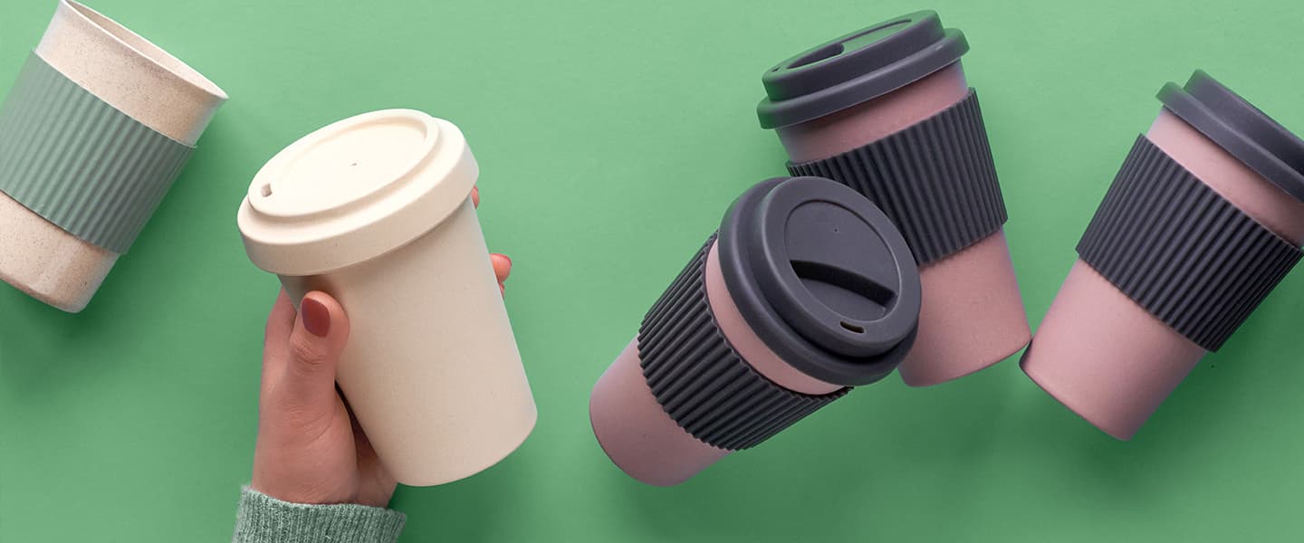 A selection of refillable coffee cups and a hand reached out to take one.