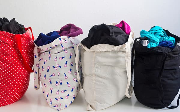 Four tote bags filled with various clothing items.