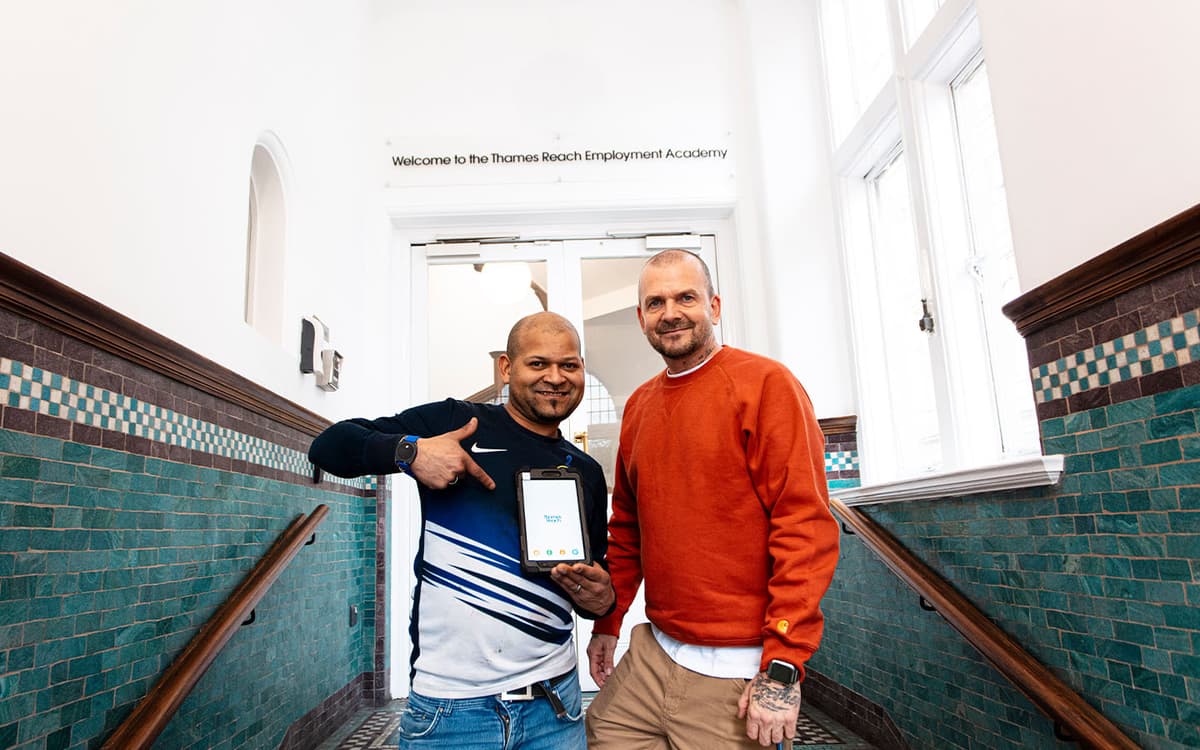 Two people smiling and pointing to a tablet donated to The Tech Lending Community Fund