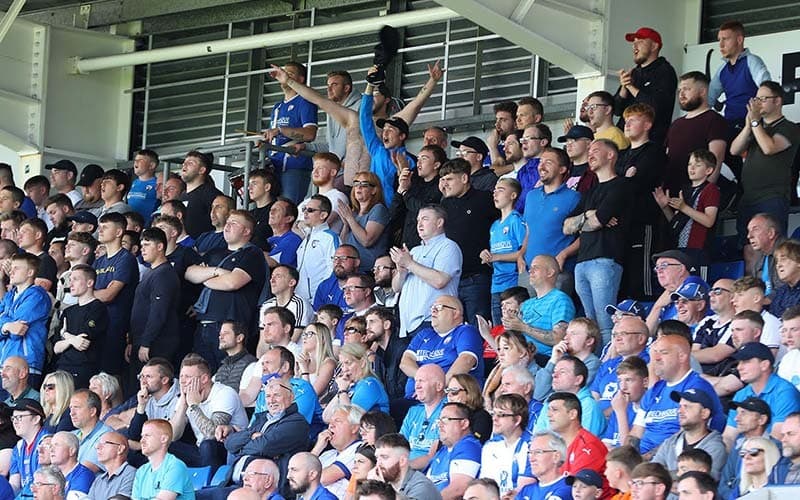 A crowd of football fans watching a game from a stand.