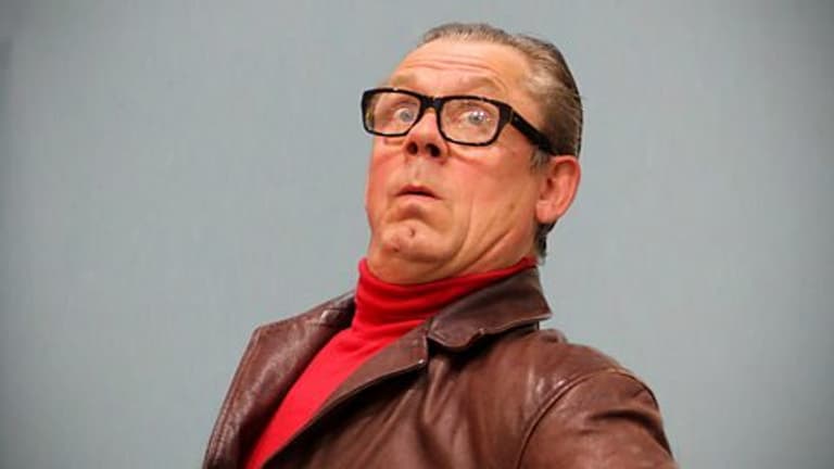 Image shows the character, John Shuttleworth, leaning back and looking at the camera with an odd expression of intrigue on his face.