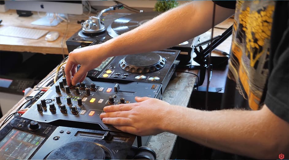 Some DJ decks, with the arms of a white person DJing in frame.