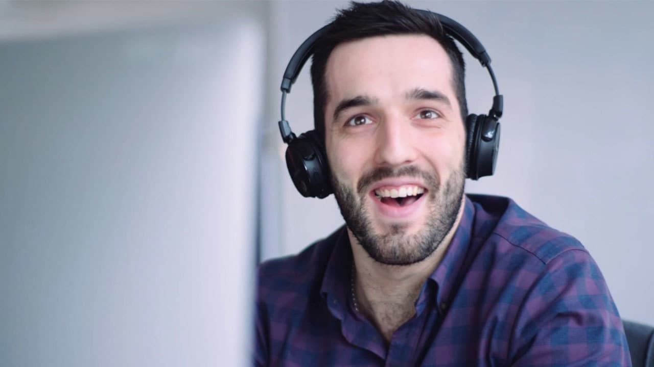 A man from the Radio.co team sat at a computer, wearing headphones and smiling.