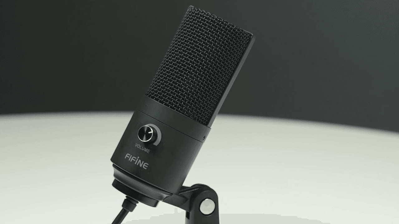 A close-up shot of the Fifine 669 microphone. A black, capsule design USB microphone on a desk stand.