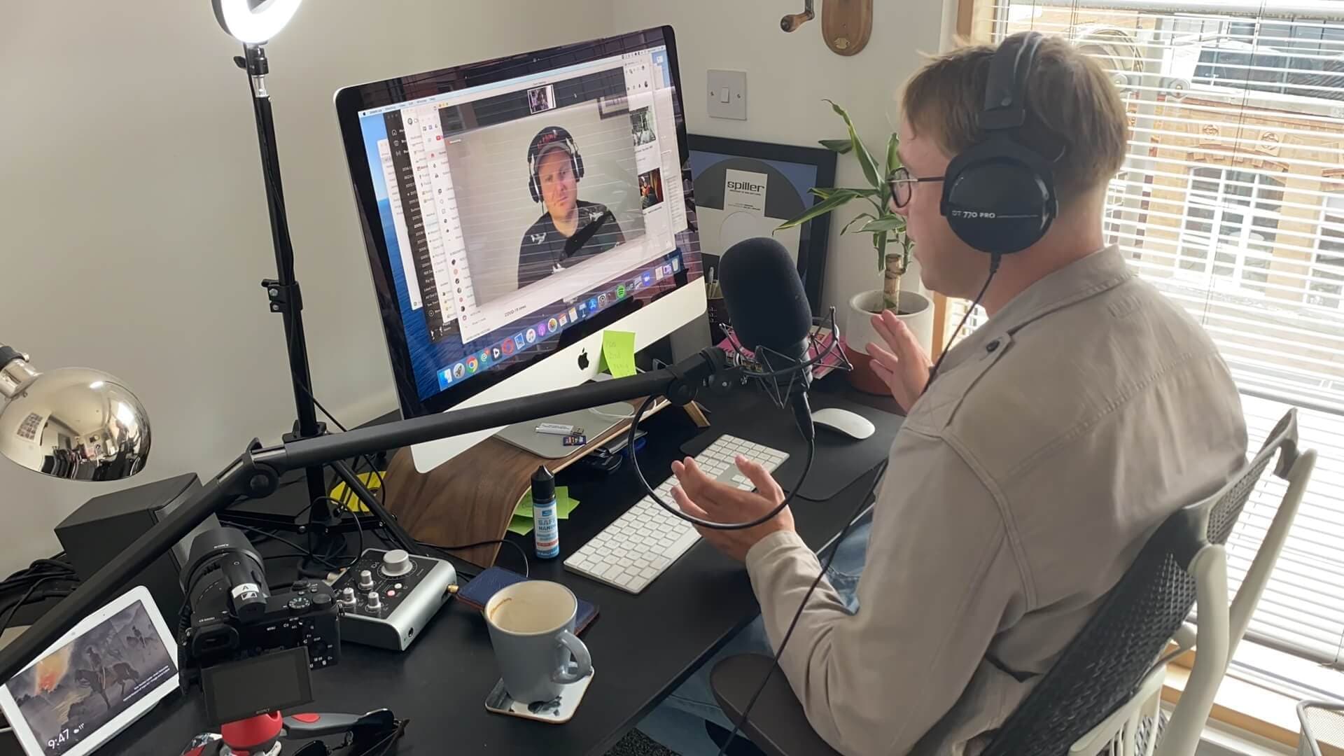 A man conducting a radio interview from a home office over Zoom.