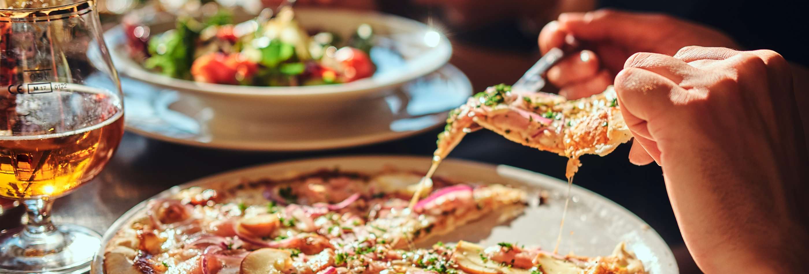 A person is cutting a piece of pizza from a delicious looking pie.