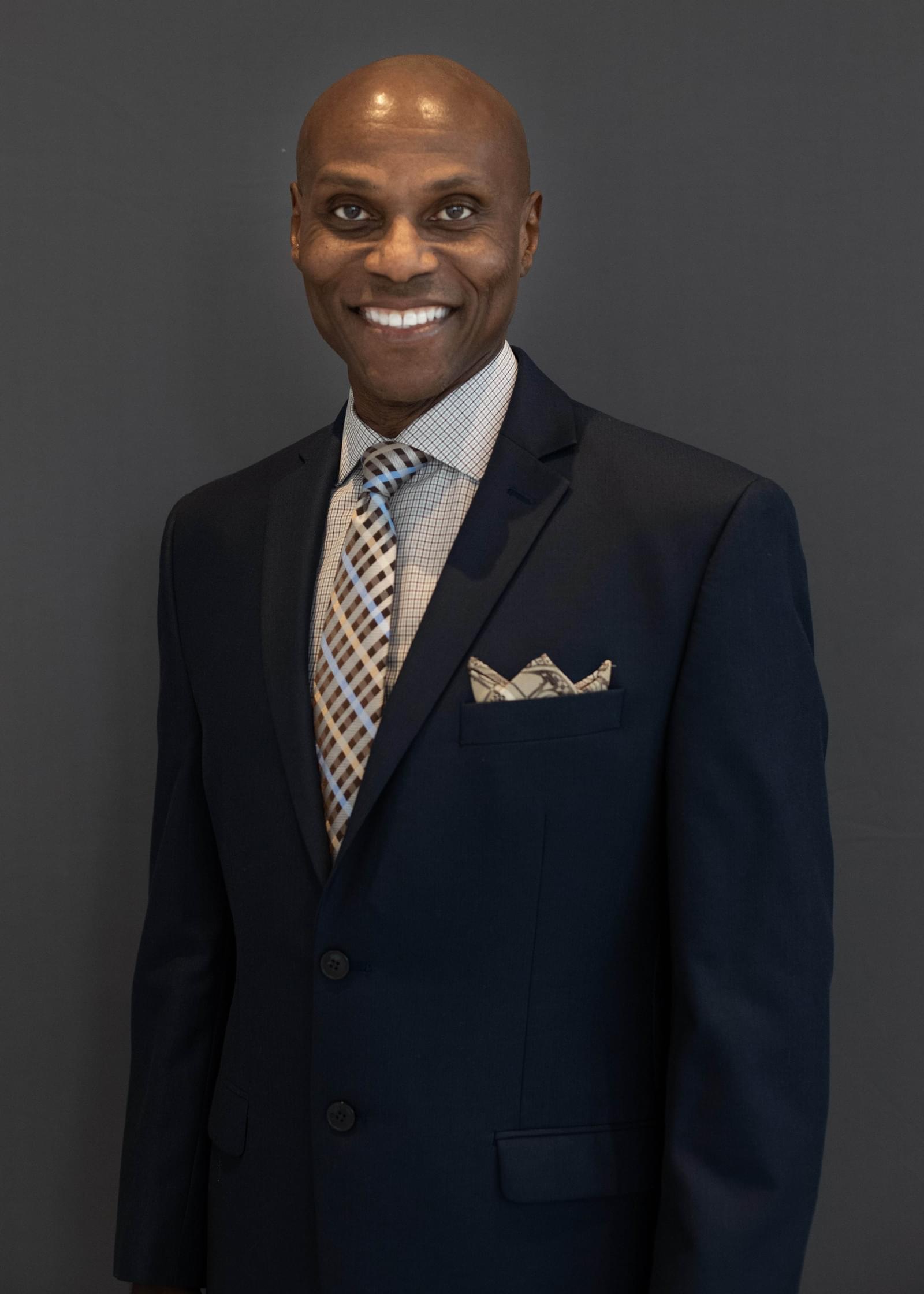 A smiling headshot photo of Cedric Layton in a suit and tie