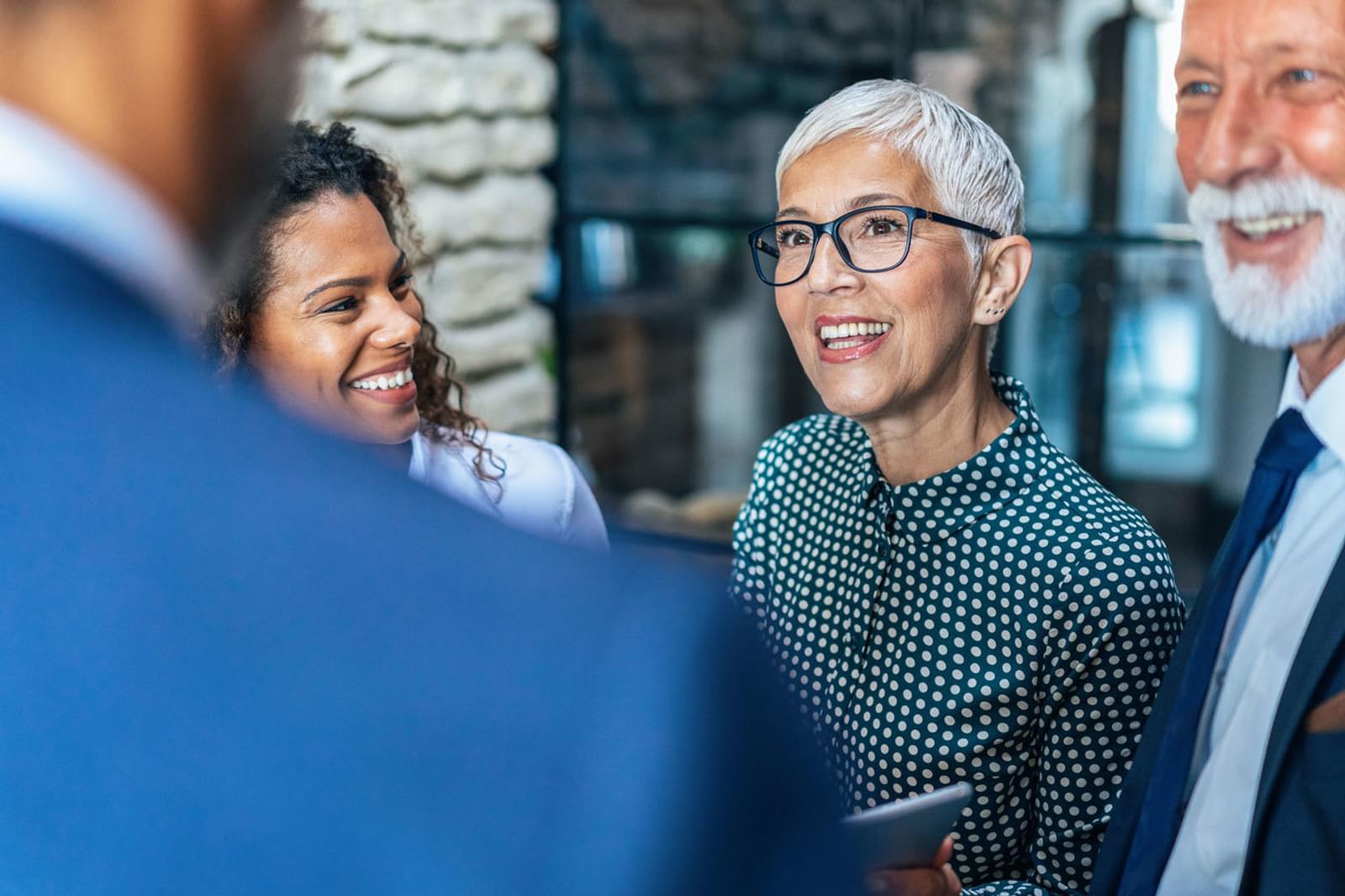 Mature woman in glasses smiles at colleagues during business discussion