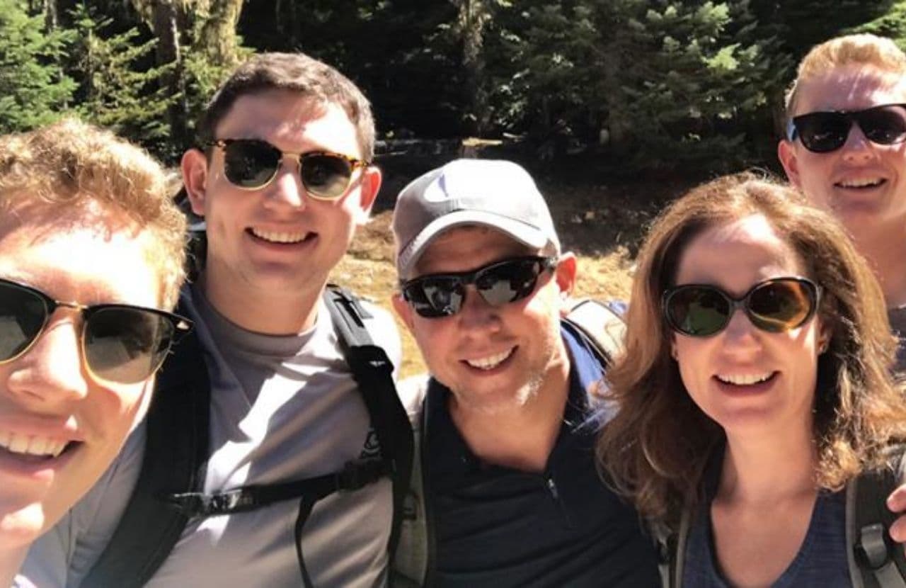 Michelle Friedman's family, all donning sunglasses smile with the woods in the background