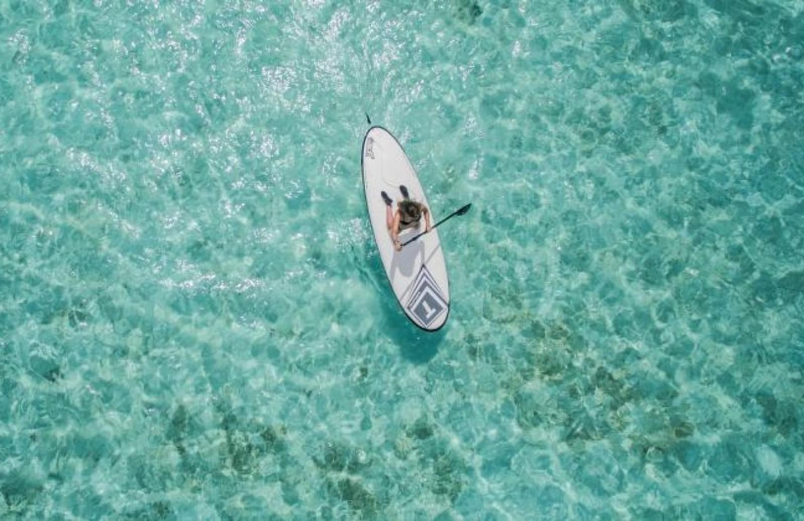 Aerial image of person on paddleboard in turquoise water